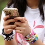 Jovem usa o celular em Sidney, na Austrália; país aprovou lei que proíbe acesso de menores de 16 anos às redes sociais — Foto: Hollie Adams/Reuters